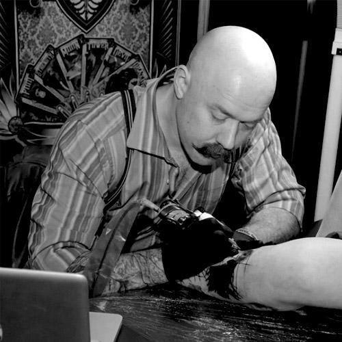 Tattoo artist using FYT Tattoo Supplies equipment in studio, New York, tattooing a client’s arm.