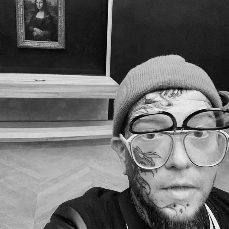 Tattooed man in double glasses and beanie at art gallery, FYT Tattoo Supplies New York