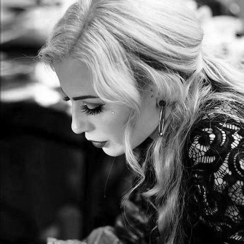 Tattoo artist with blonde hair and lace top working, FYT Tattoo Supplies New York