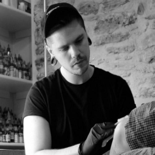 Tattoo artist using FYT tattoo supplies in New York studio with brick wall background