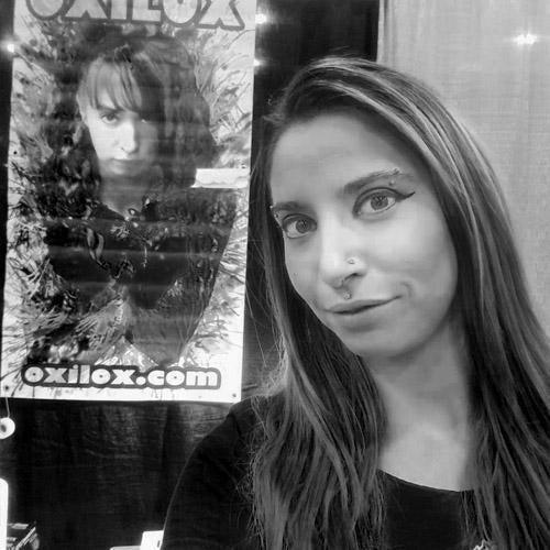 Woman at a tattoo supplies event booth with poster, FYT Tattoo Supplies New York